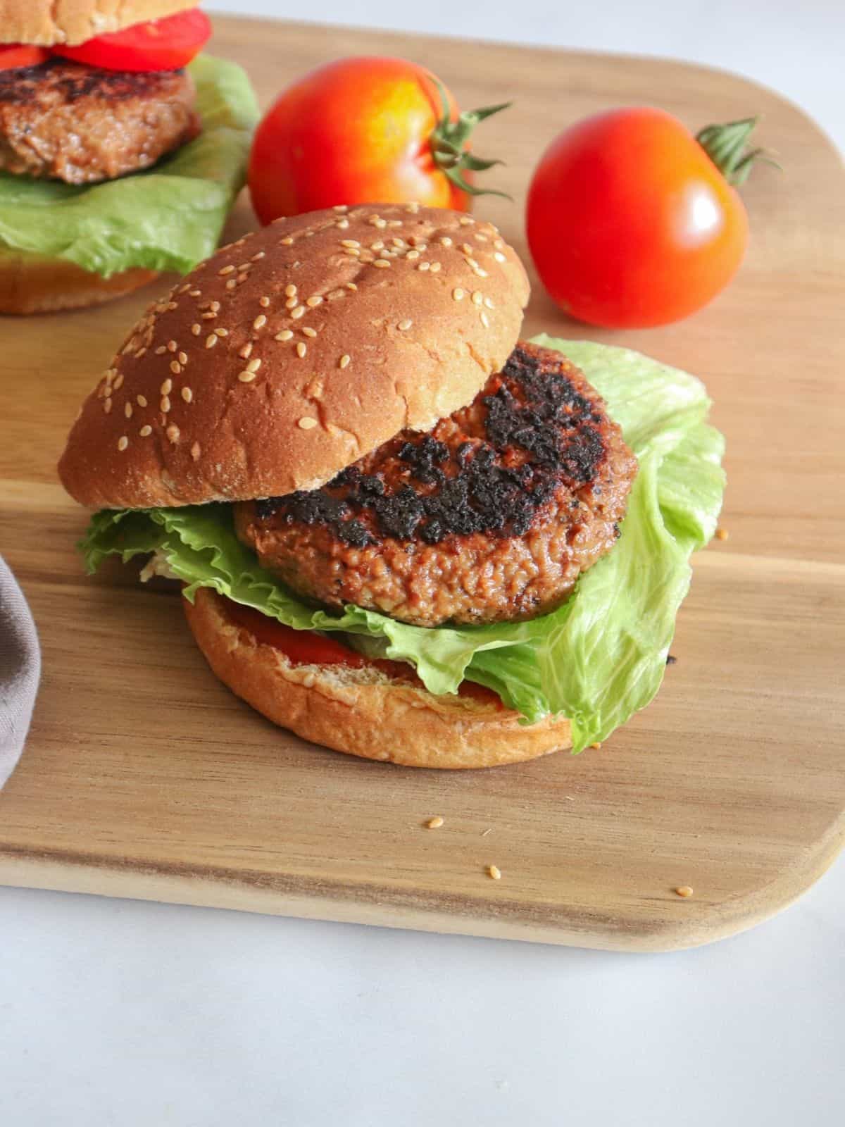 patty on bun with lettuce tomatoes on wooden surface