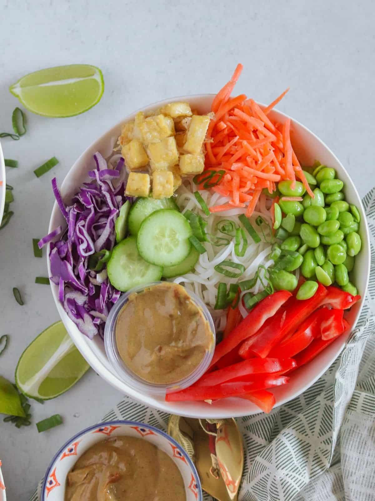 Colorful bowl on white counter with sliced limes and green onions