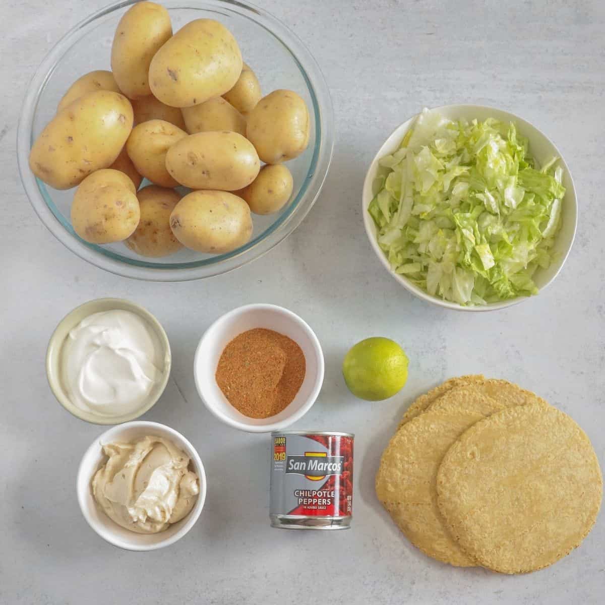 tortillas, lettuce, potatoes, spices on white counter