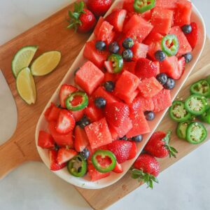 assorted fruits on wooden cutting board with peppers