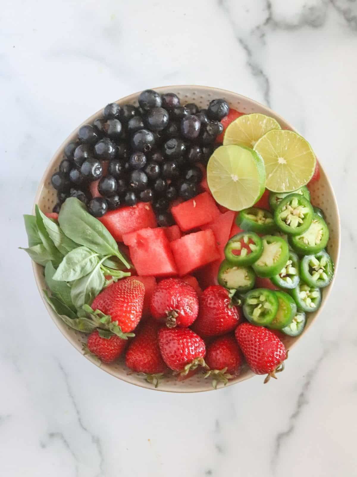 Assorted fruits in bowl with herbs and peppers