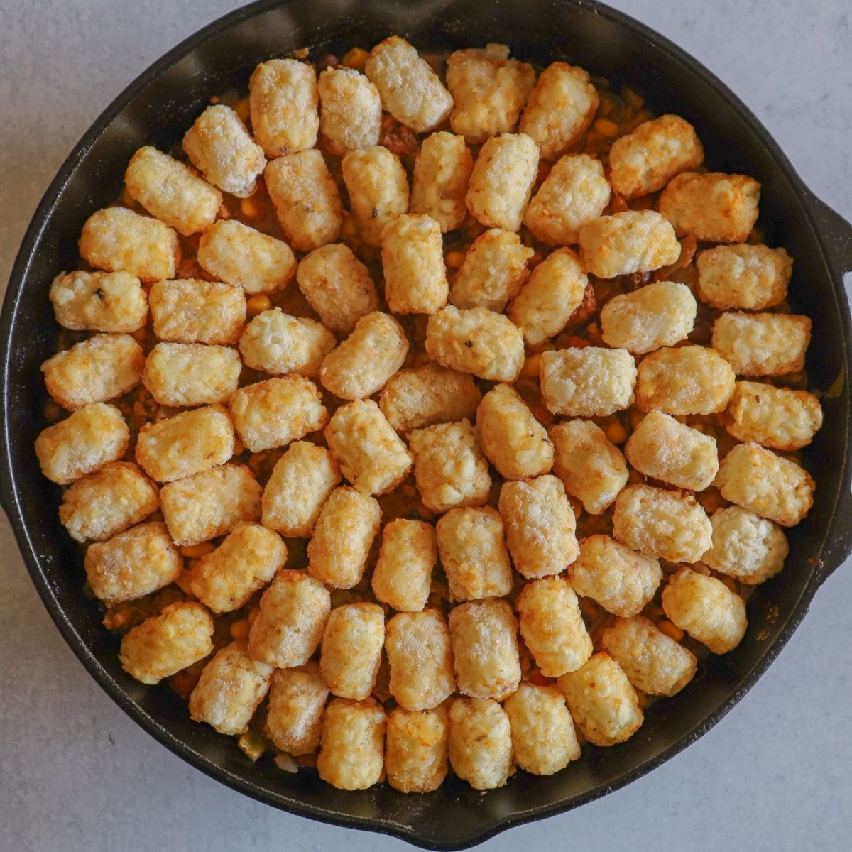 Cast Iron Skillet on grey surface with potato puffs