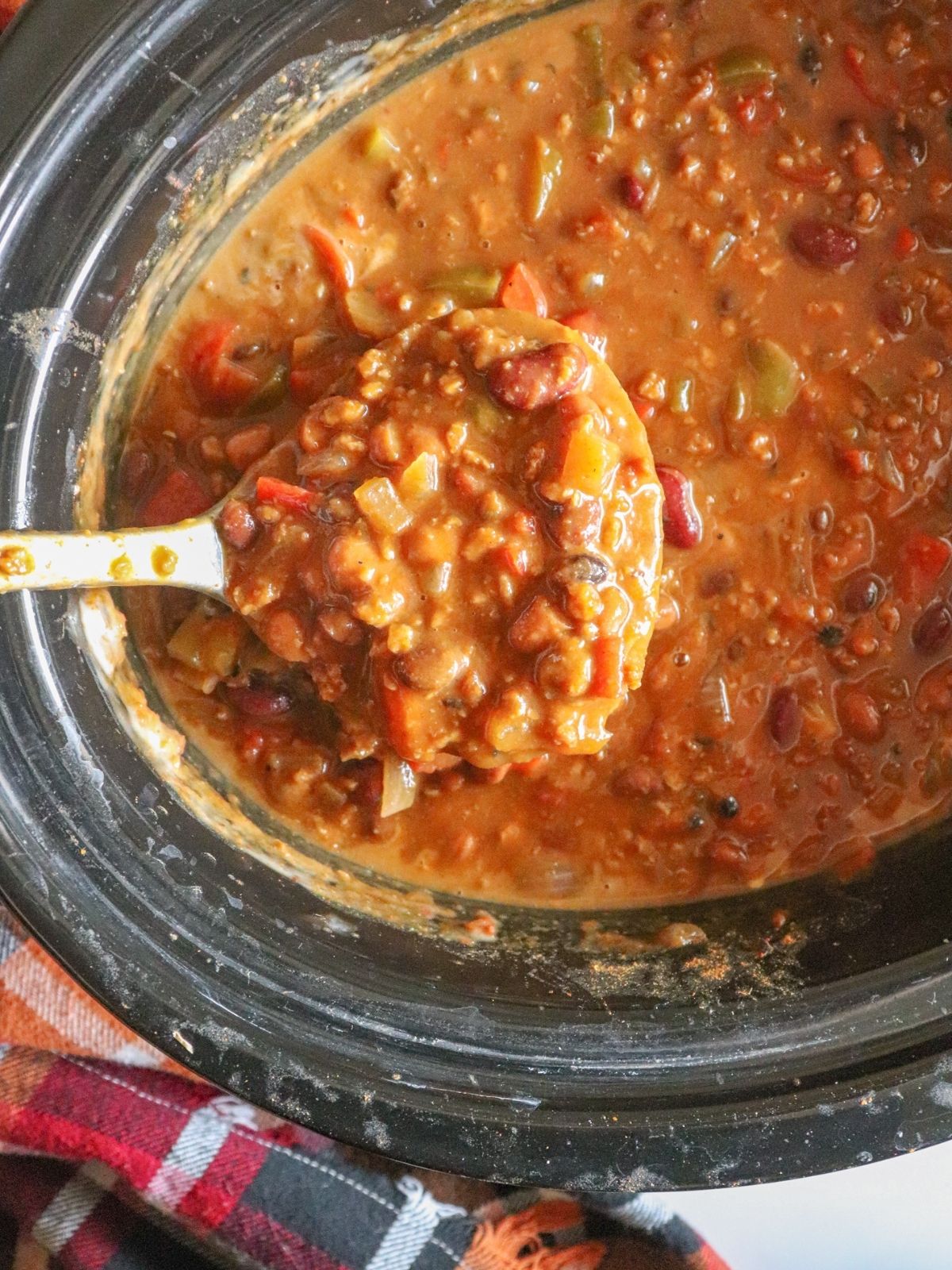 Photo of crockpot full of chili with ladle spooning some of it out. 