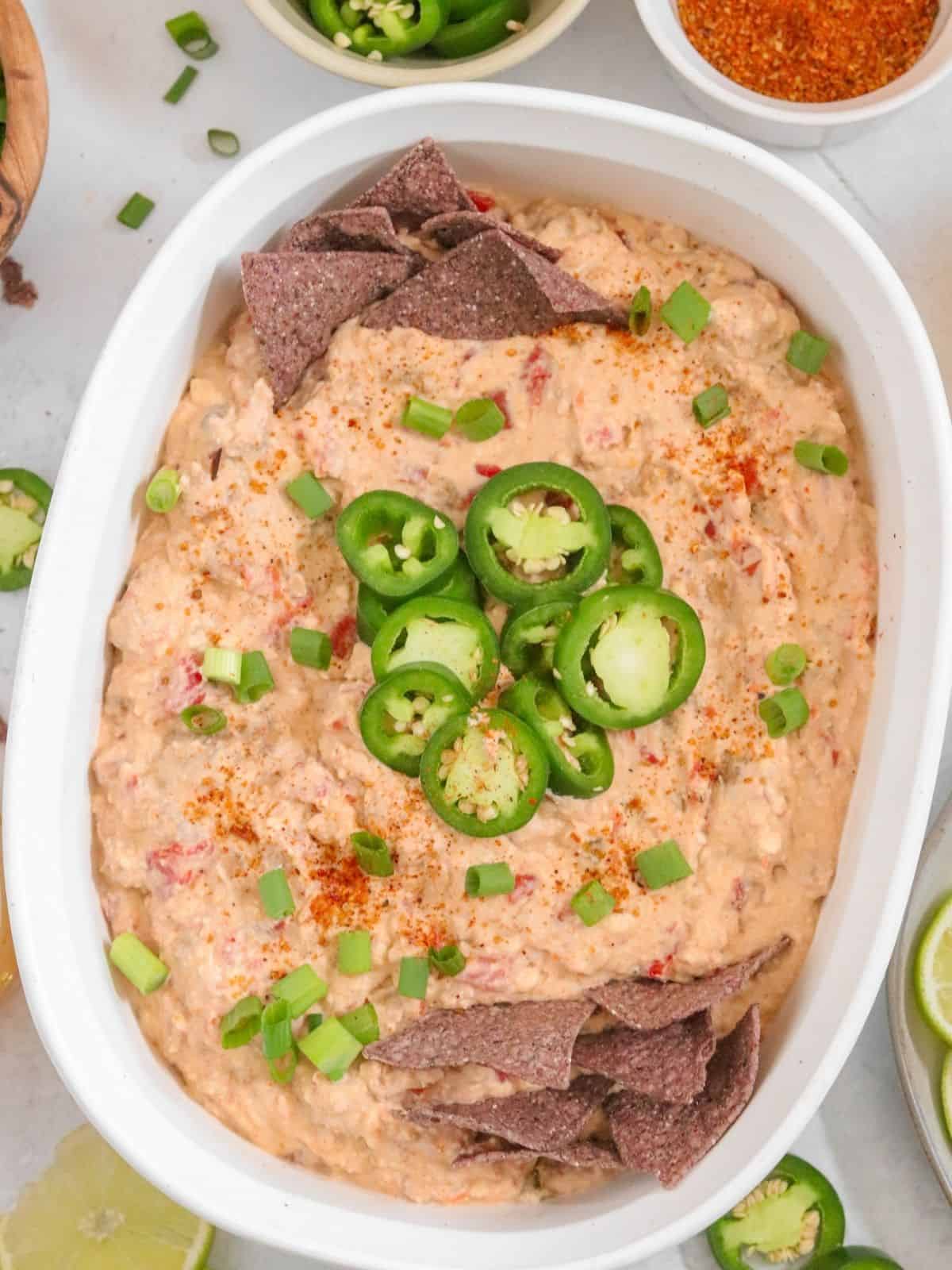 Bowl filled with creamy recipe topped with jalapenos and tortilla chips