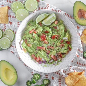 Bowl of mashed avocado with limes and chips