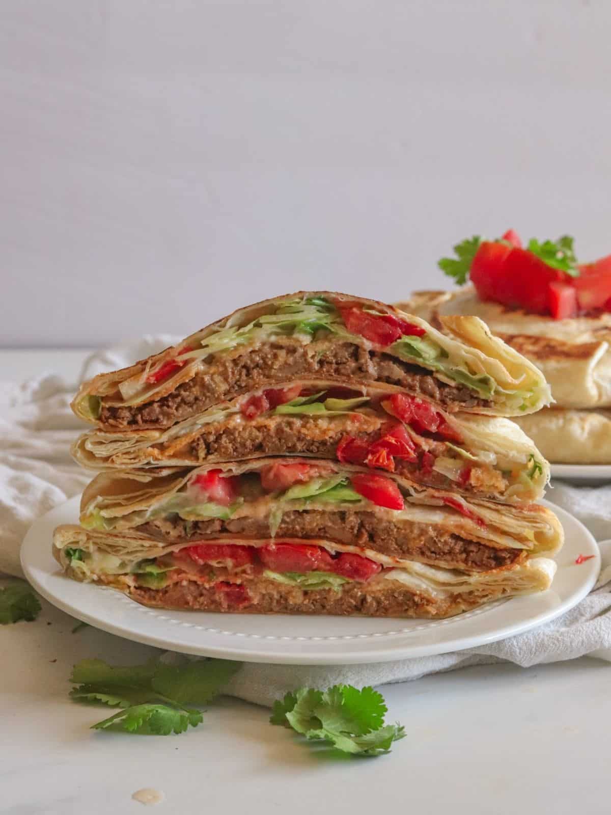 Stacked tortillas that are filled on white plate