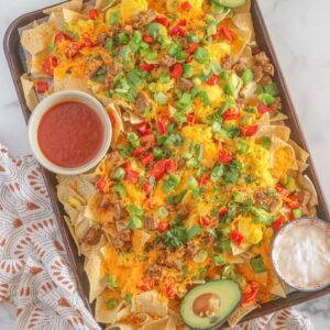 sheet pan with tortilla chips salsa and toppings on white surface
