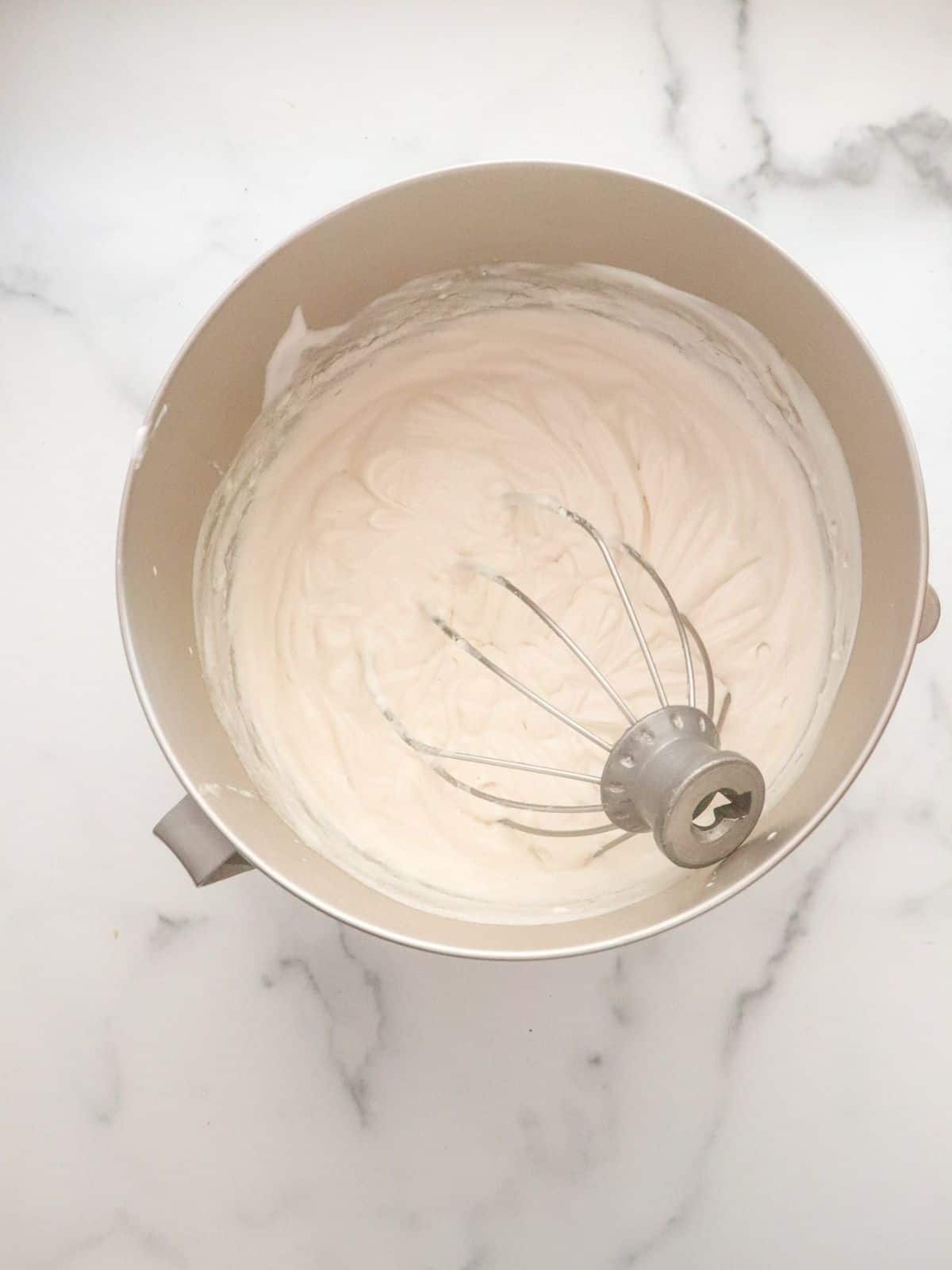 Whipped cream cheese in bowl with whisk