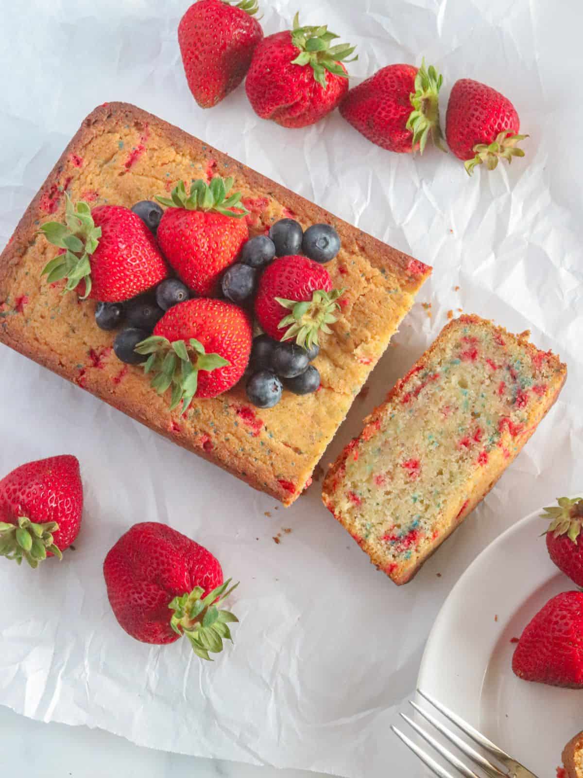 Sliced dessert with strawberries and blueberries on parchment paper