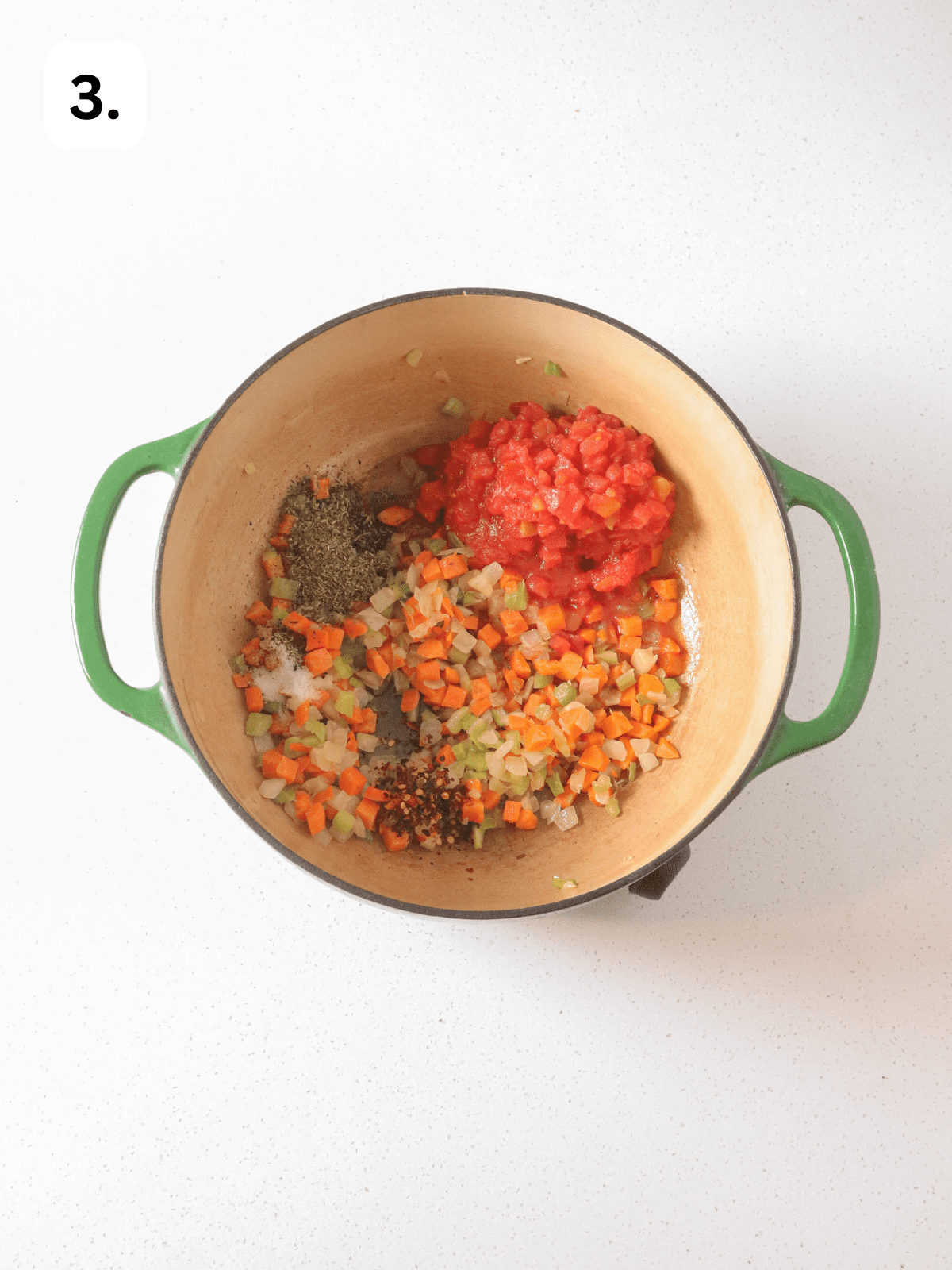 Green dutch oven with tomatoes, mirepoix and seasonings